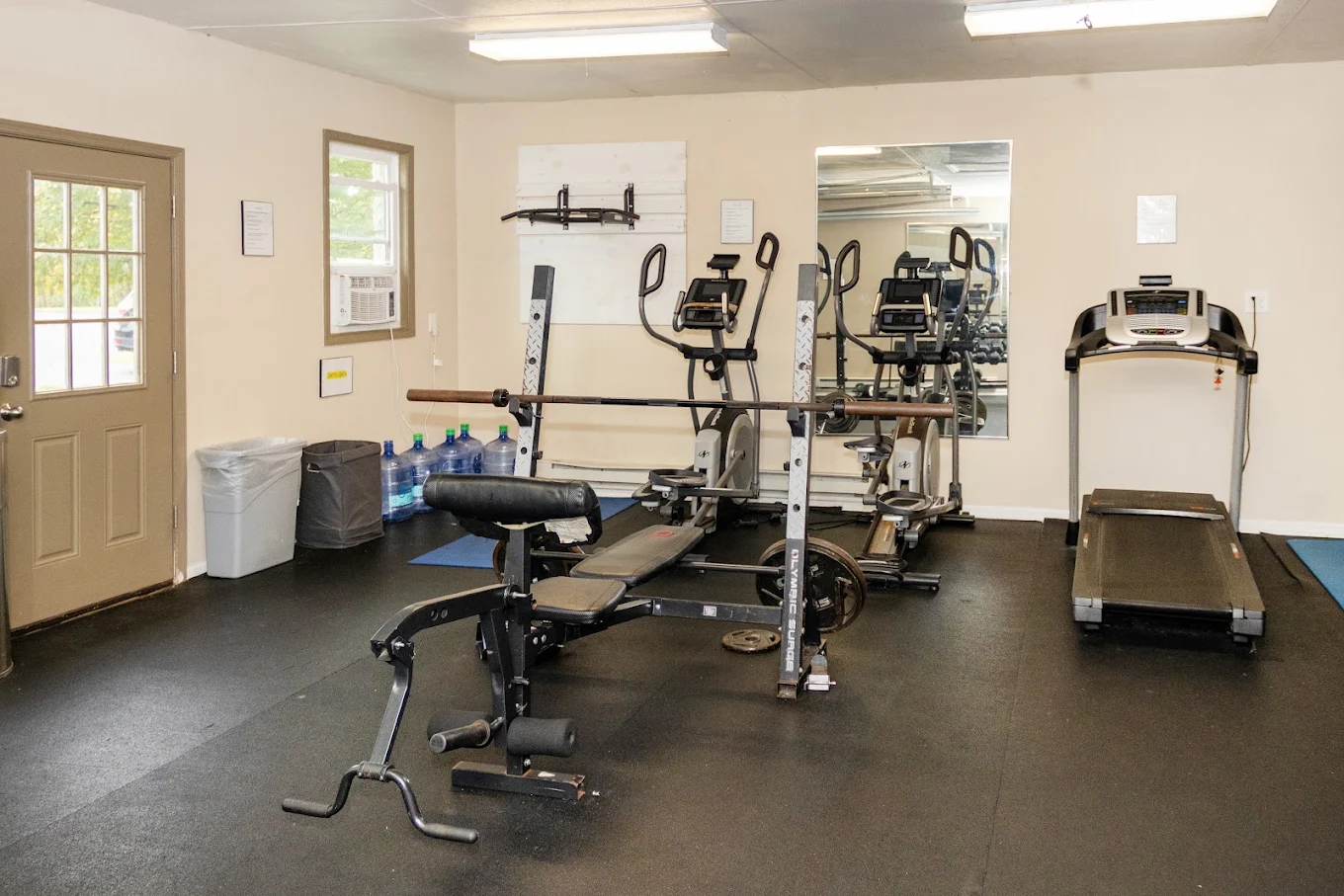 Fitness room with weight machines, benches, and treadmill