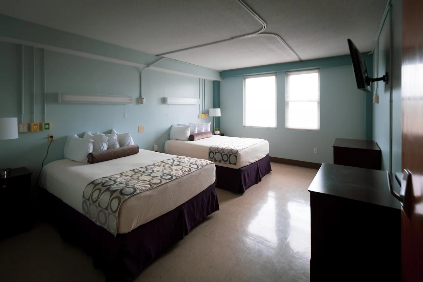 Recovery room with two queen beds, large windows, and wall-mounted television at NOLA Detox