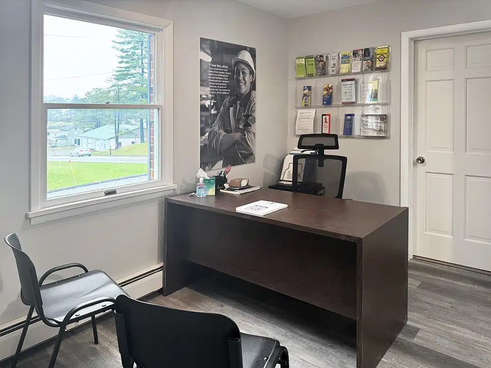 Office with desk, chairs, and brochure display on wall