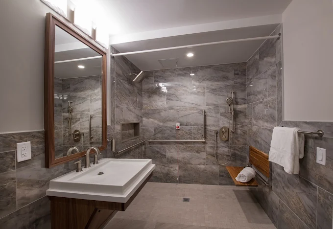 Spacious gray-tiled bathroom with walk-in shower and bench