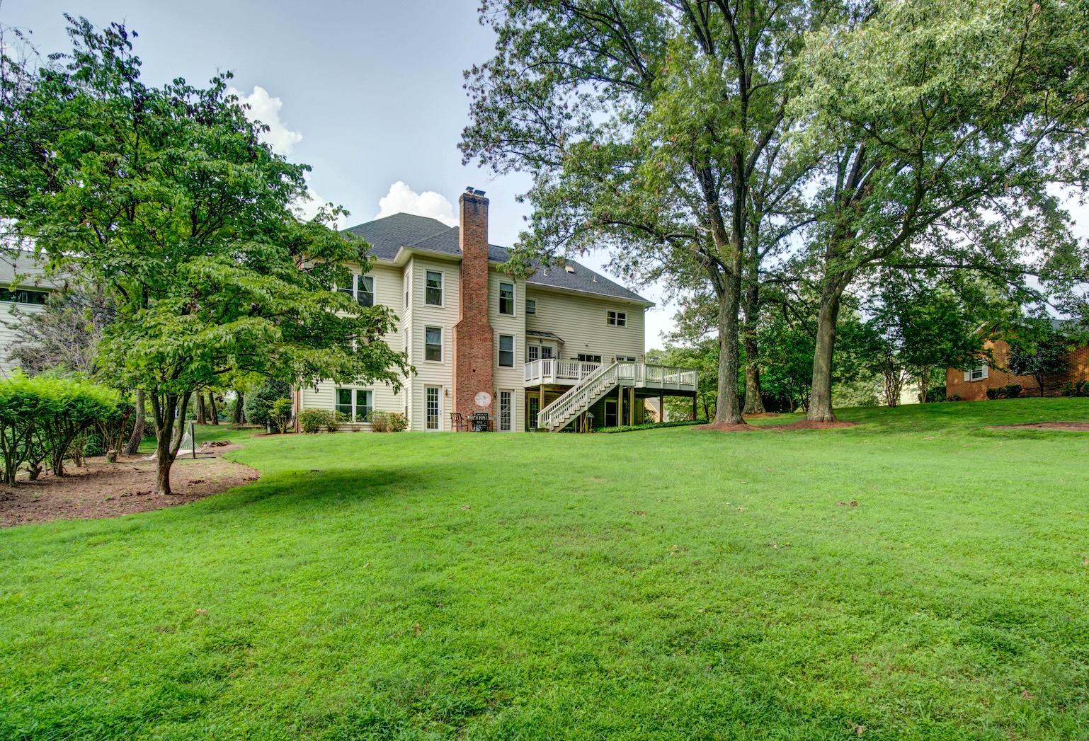 A rehab facility’s backyard with lush green lawn and mature trees