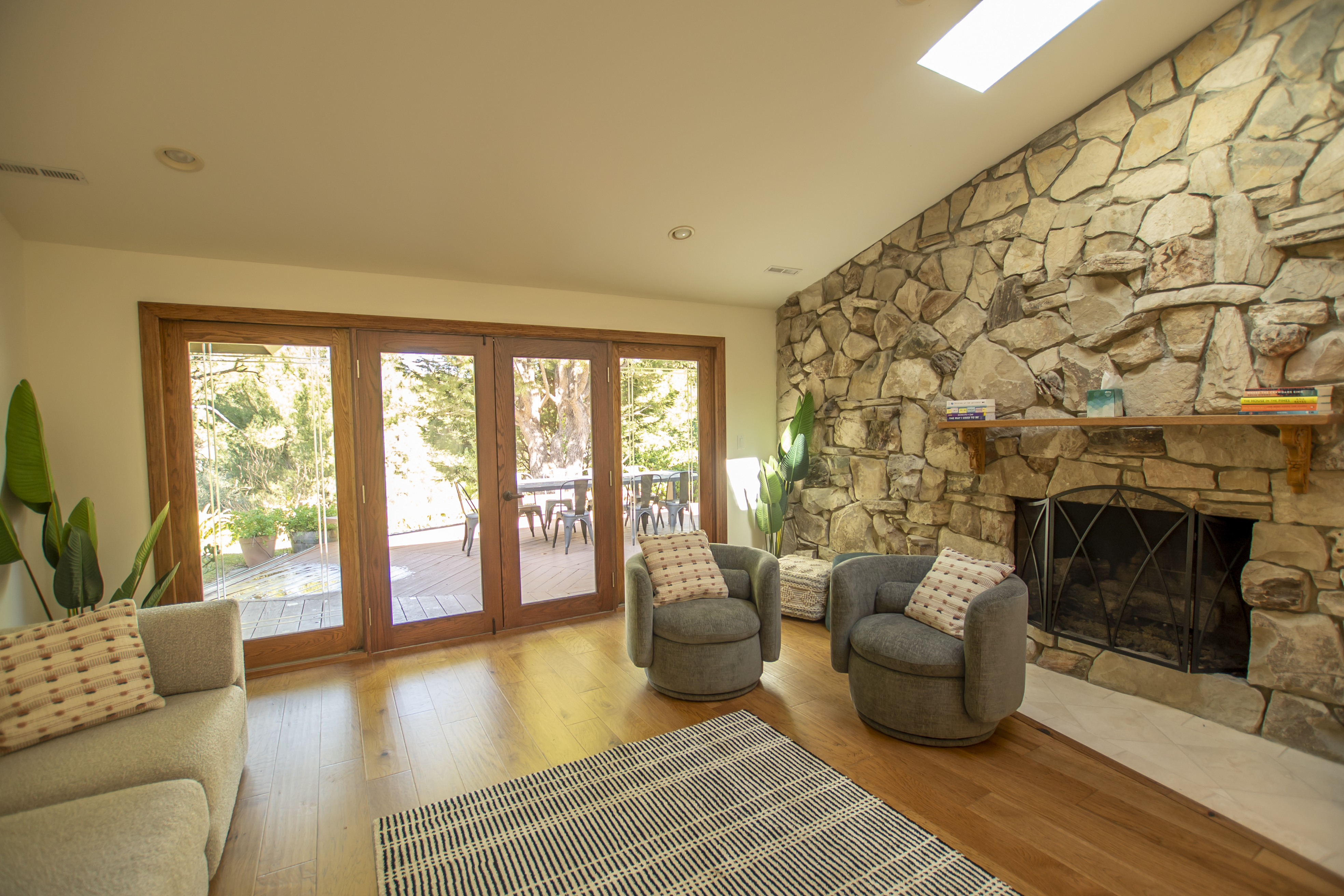 A cozy sitting area with a stone fireplace and outdoor deck access.