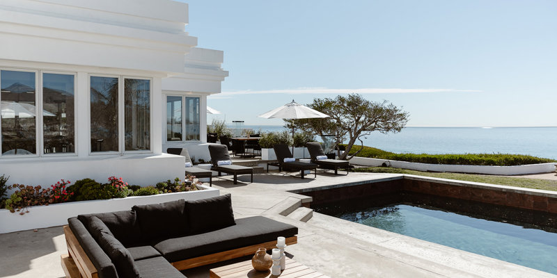  Luxurious outdoor seating area by a serene pool, offering breathtaking ocean views, shaded lounge chairs, and a modern, elegant ambiance.