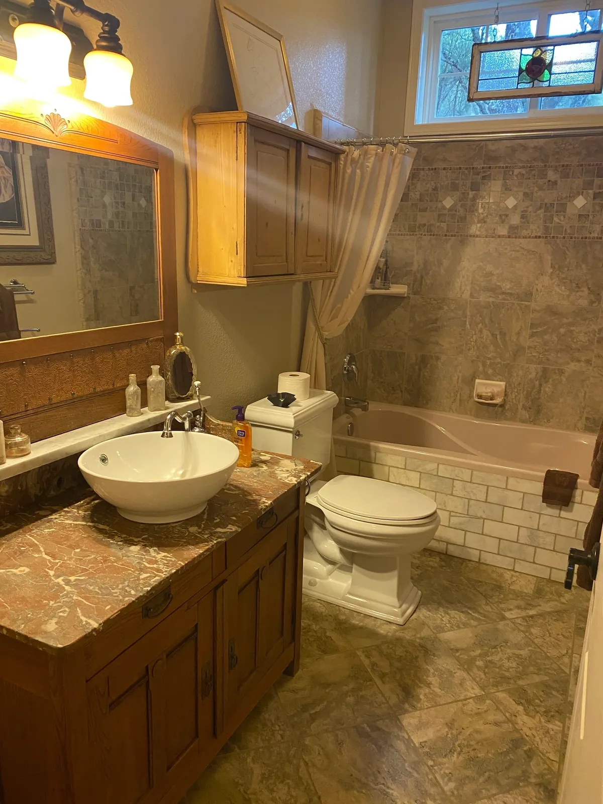 Bathroom with vanity, toilet, and tiled shower-tub combo