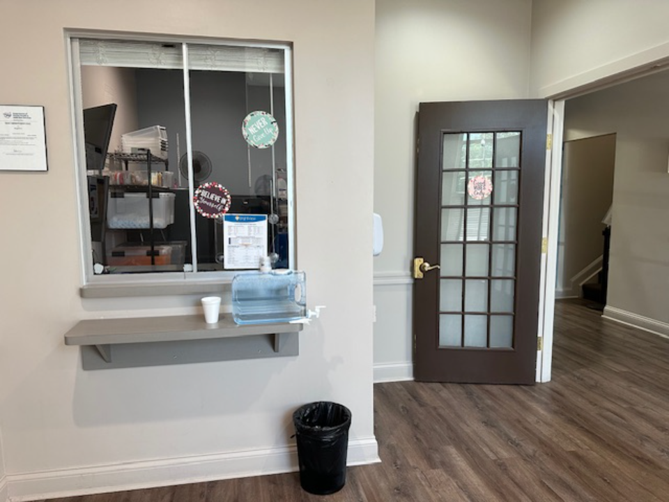 BrightView Health check-in service window with counter, water dispenser, open doorway, and wood flooring