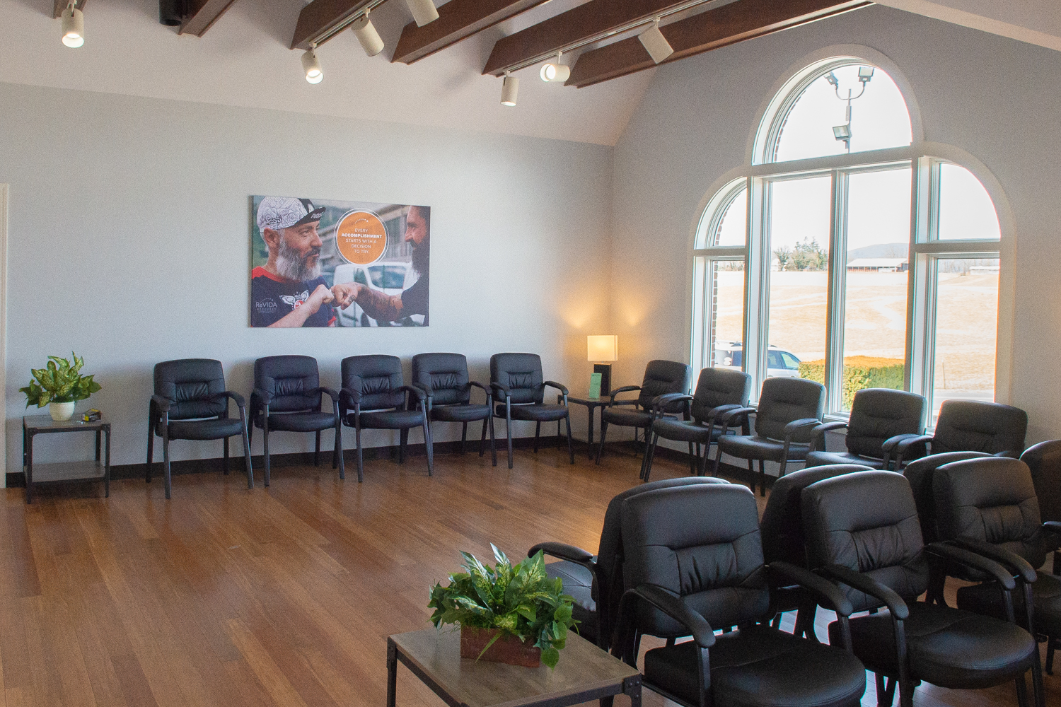 Bright group therapy room with chairs and large arched windows