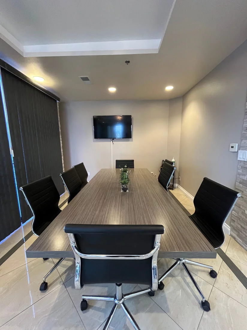 Conference table with black chairs and wall-mounted TV
