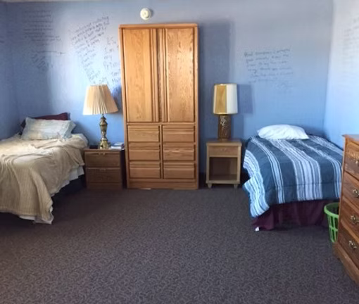 Shared residential bedroom with two twin beds and basic furnishings