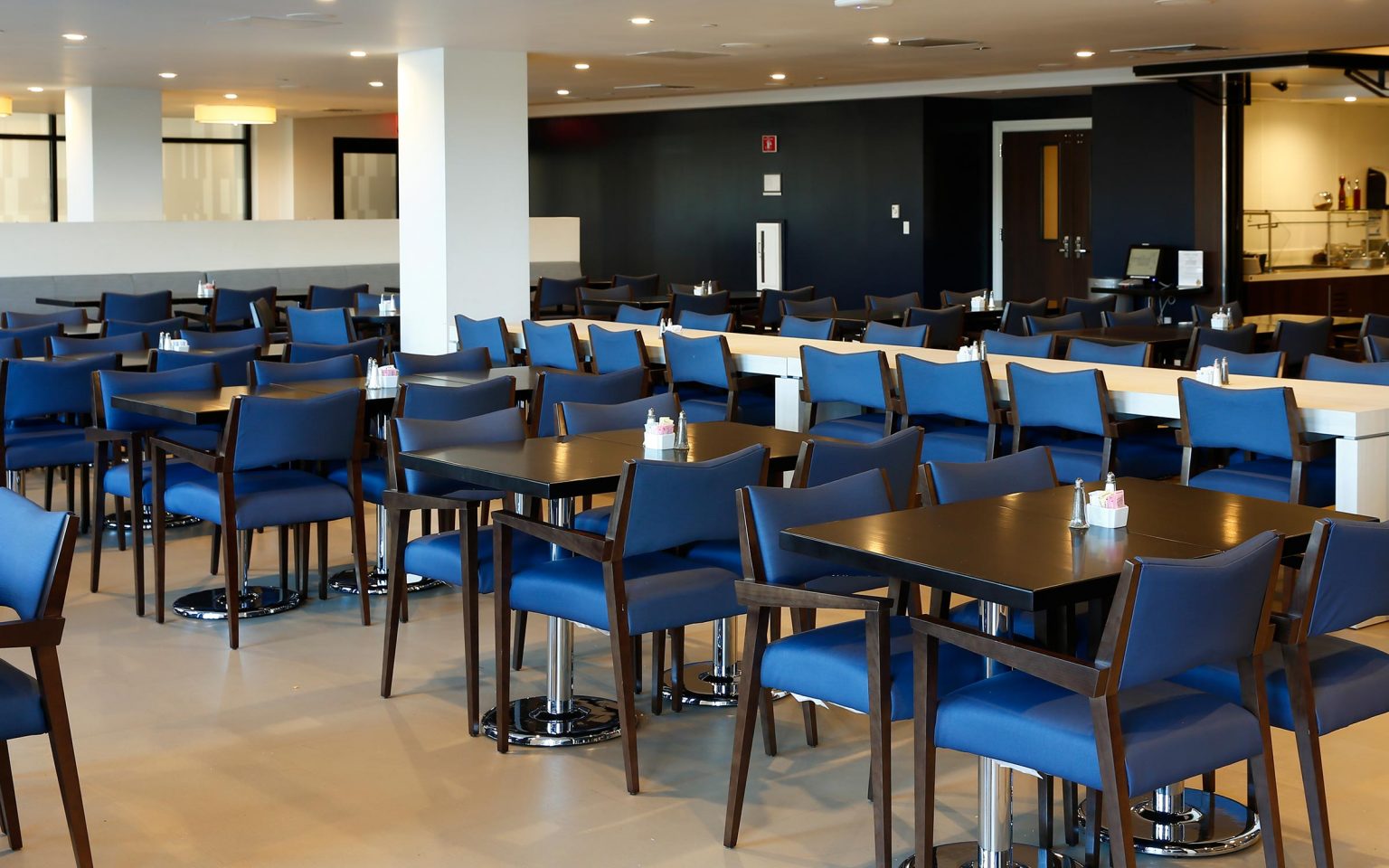 Modern dining area with blue chairs and black tables.