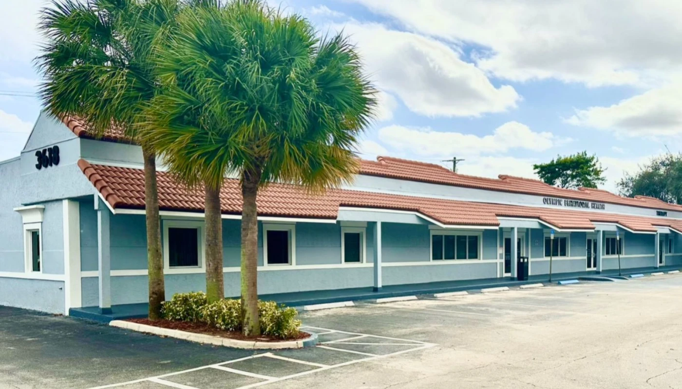 Exterior of Olympic Behavioral Health facility with palm trees and parking.
