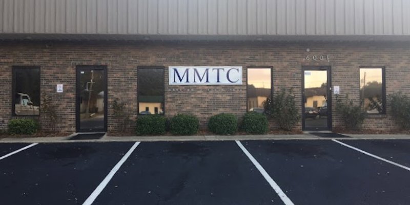 A brick building with a simple, clear "MMTC" sign, featuring neatly maintained landscaping and an easily accessible parking lot.