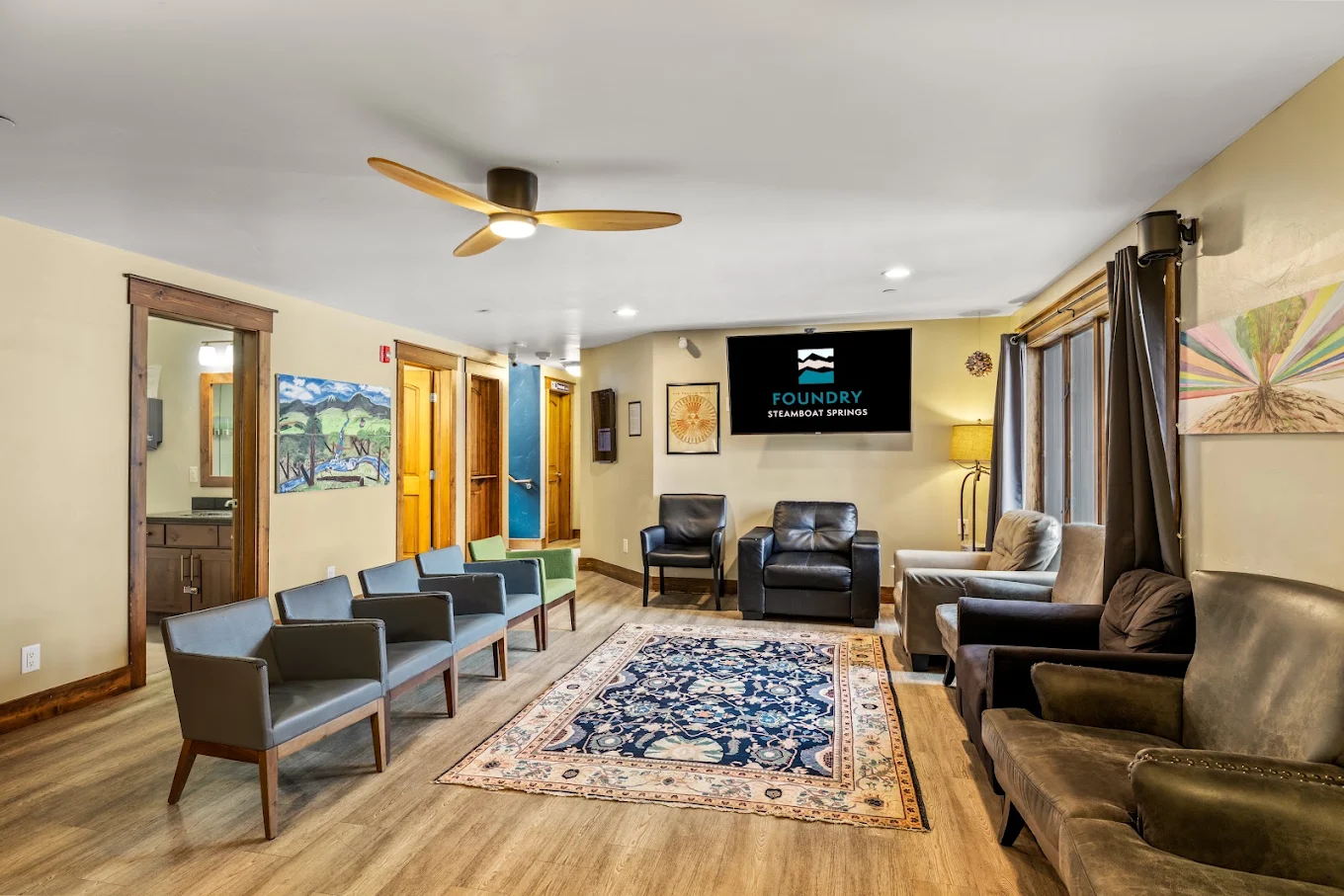 Welcoming therapy area with assorted armchairs arranged around a patterned rug and Foundry display screen