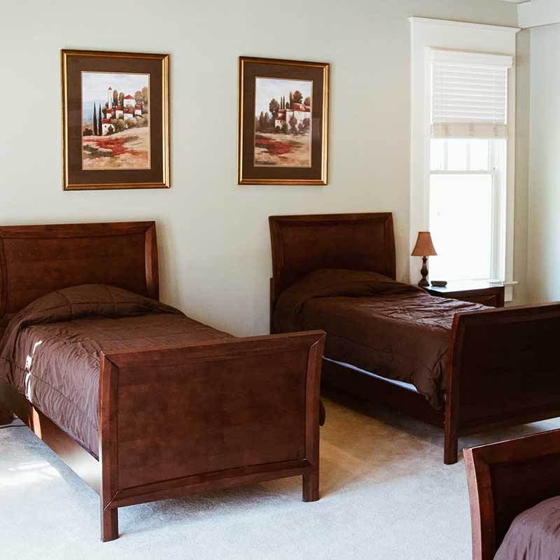 Bedroom with two single beds, wooden furniture, and framed artwork