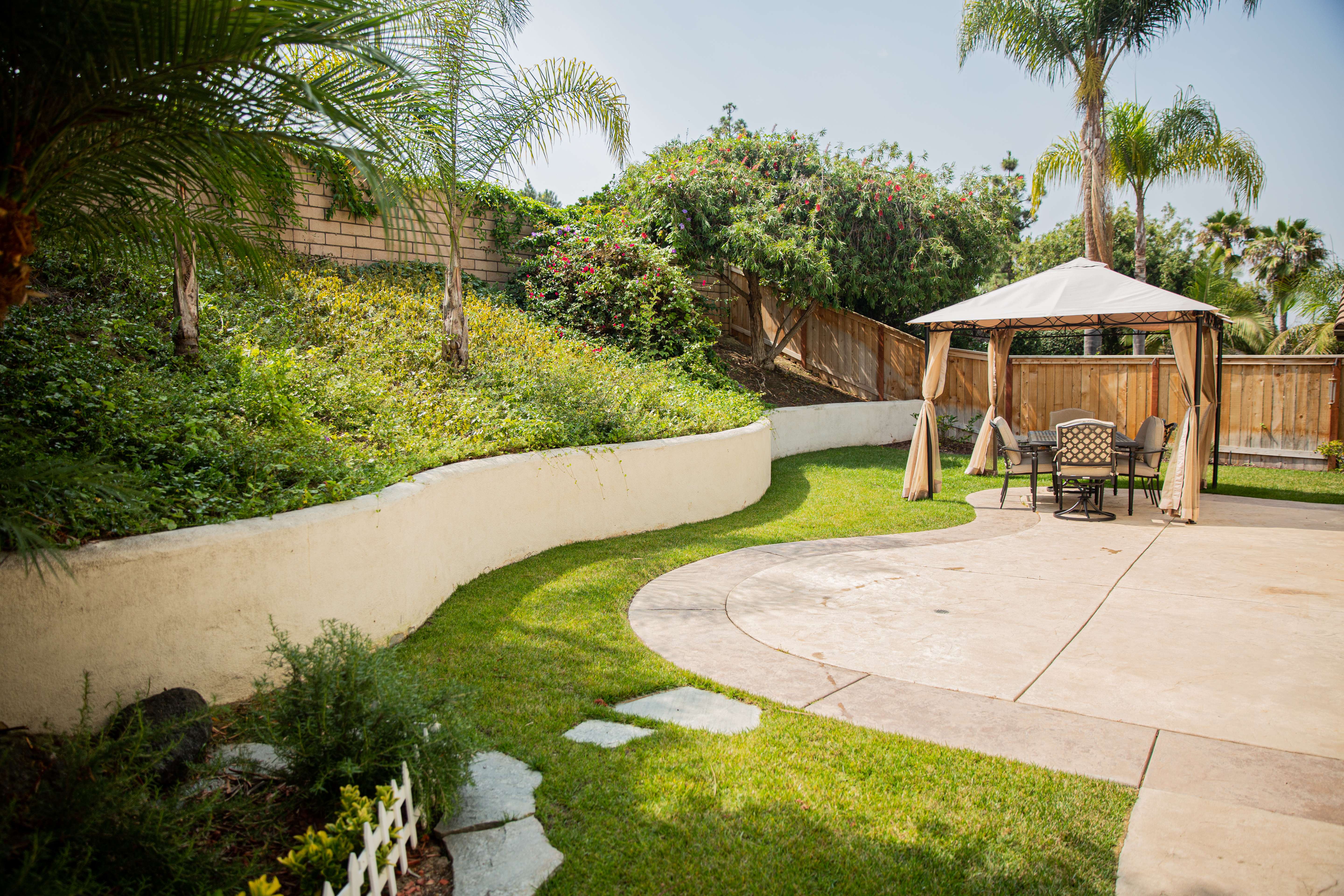 Covered patio with chairs in a fenced backyard