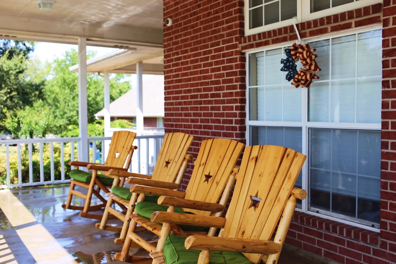 Covered porch with a row of wooden rocking chairs beside the red-brick exterior of Discovery Point Retreat