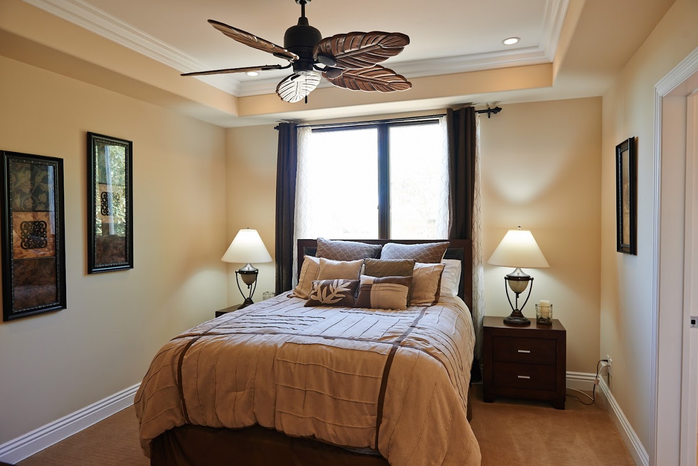 Warm bedroom with a ceiling fan and bedside lamps.