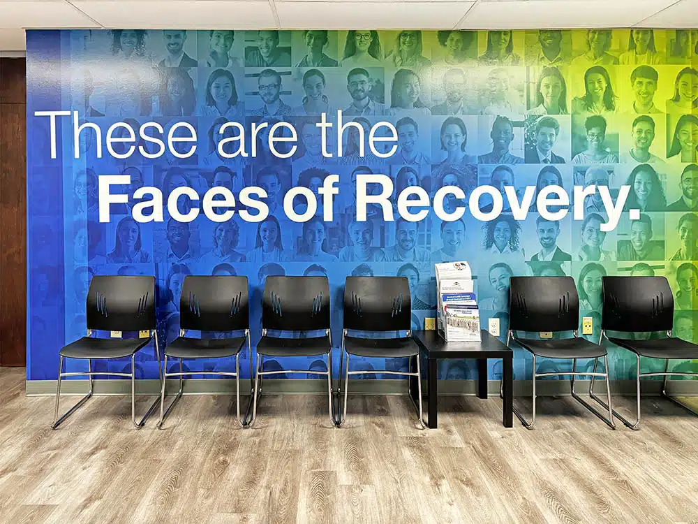 Row of chairs in front of Faces of Recovery wall mural