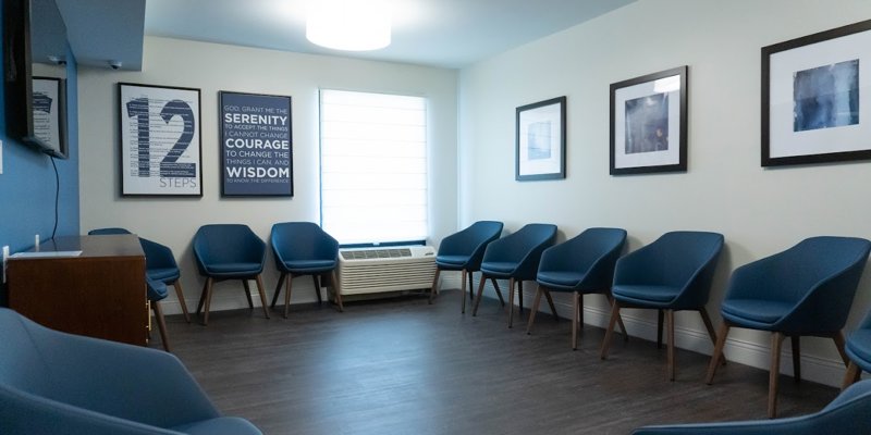 A welcoming meeting room with a circle of blue chairs and motivational posters on the walls, providing a serene space for group discussions.