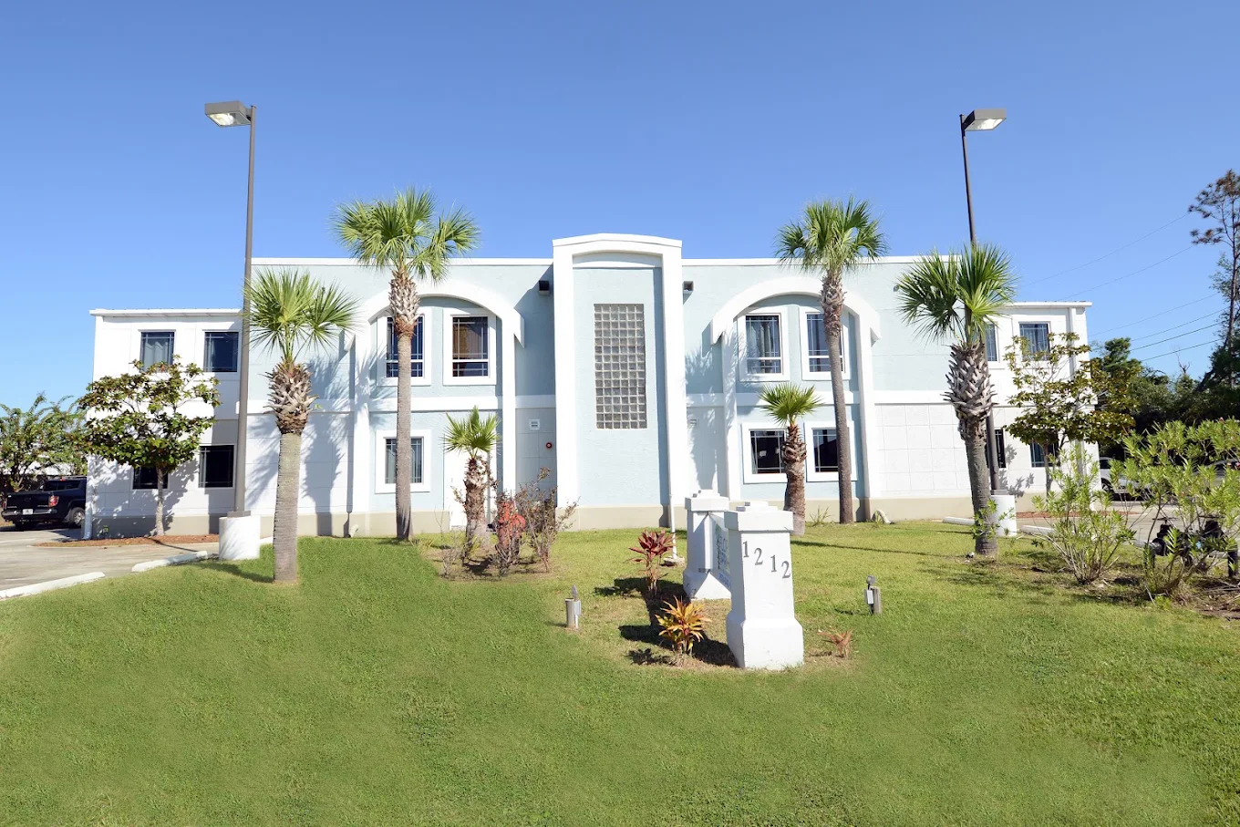 Two-story treatment center with palm trees and lawn
