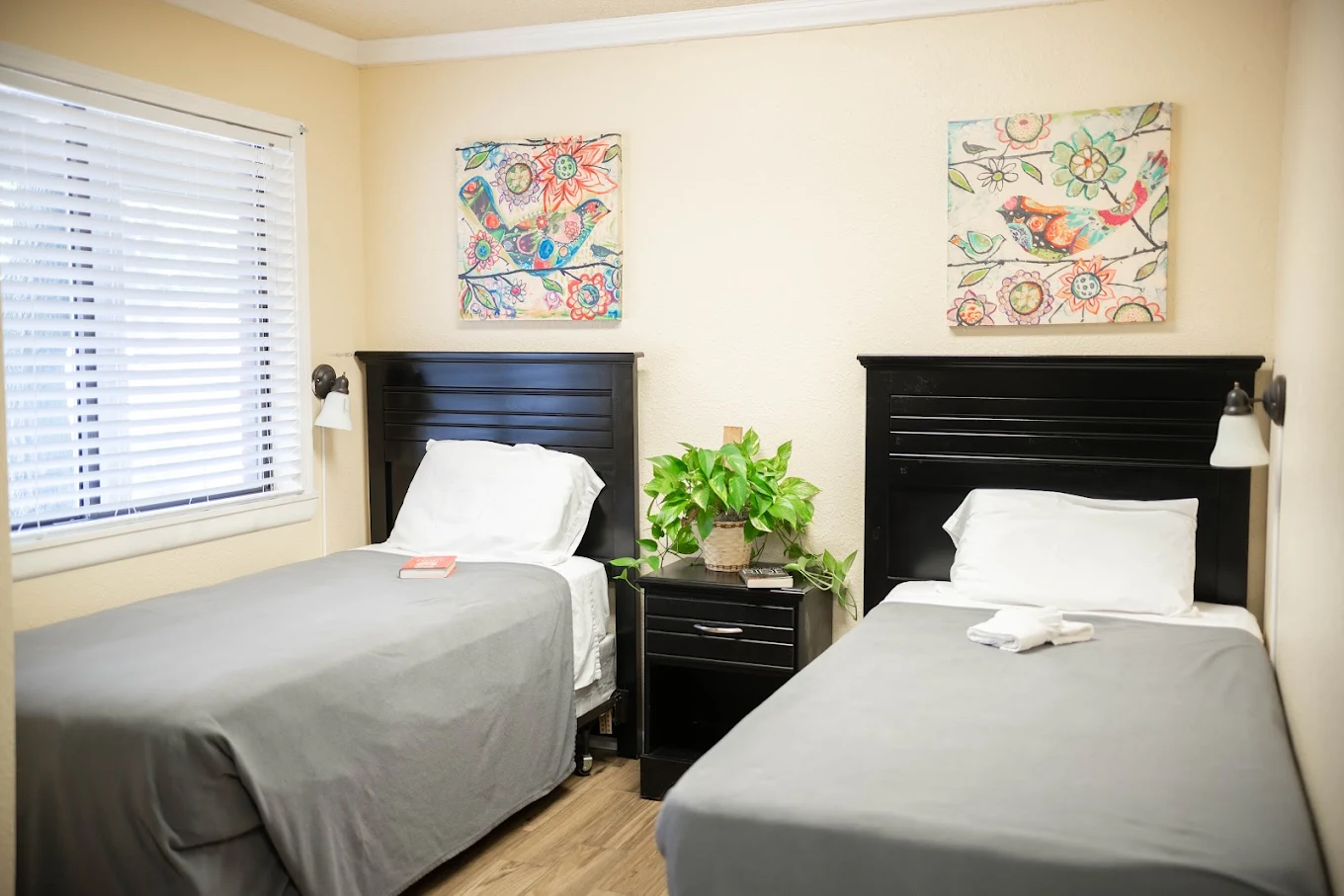 Two twin beds with black headboards and floral artwork