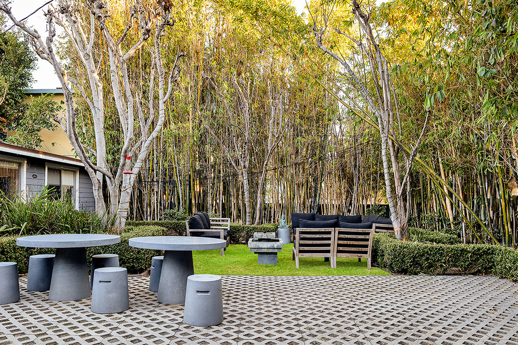 Outdoor seating area with round tables, chairs, and bamboo trees
