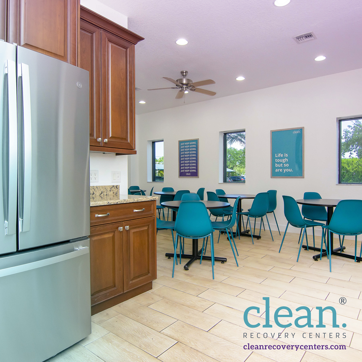 Dining area with teal chairs and wooden kitchen cabinets