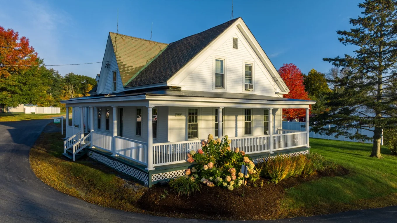 Residential house with wraparound porch and landscaped yard