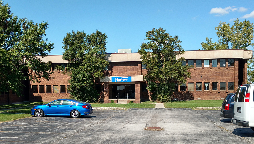 Brick rehab facility building with parking and trees in front