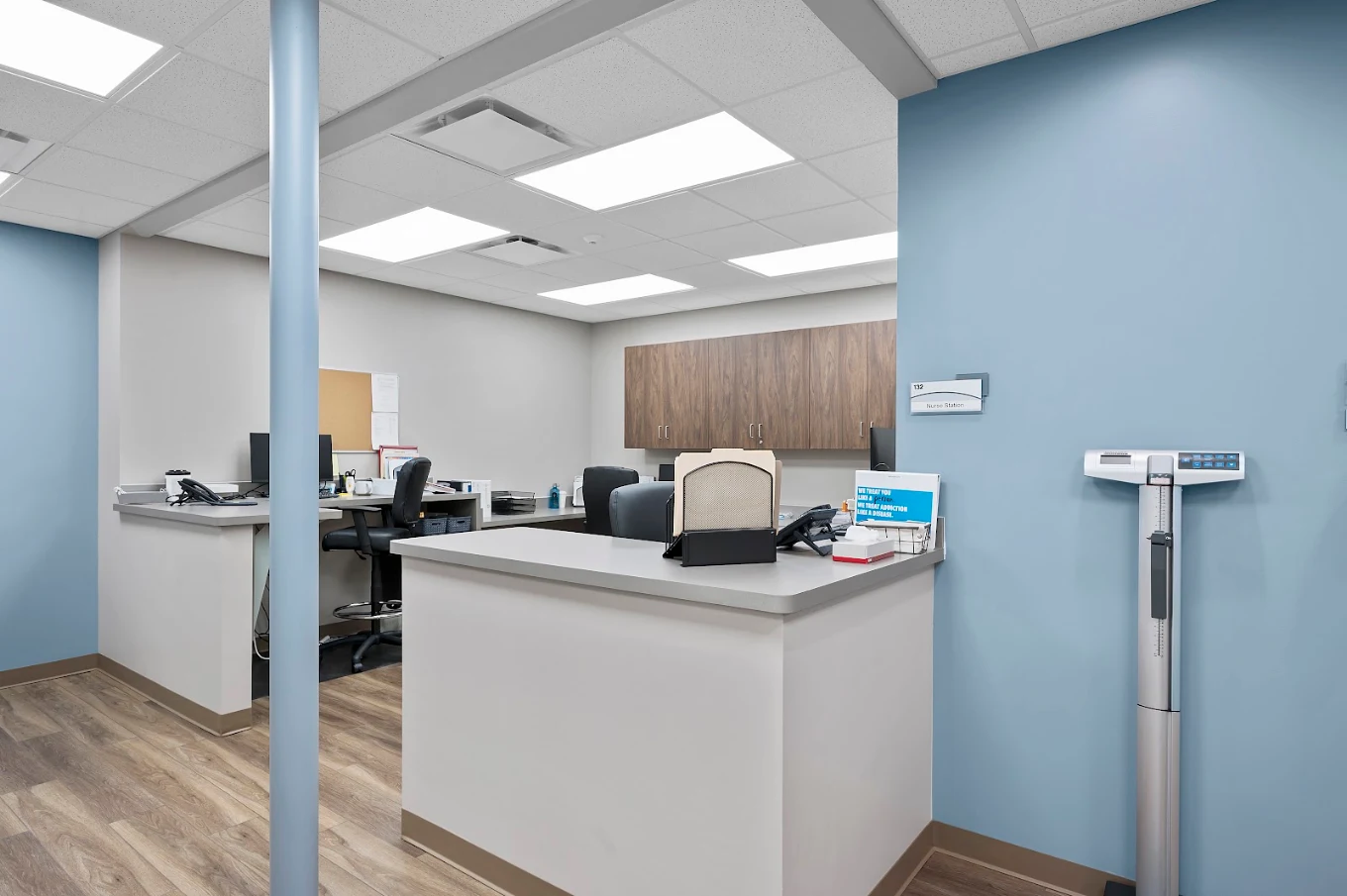 Nurse station with work counters, cabinets, computers, and medical scale