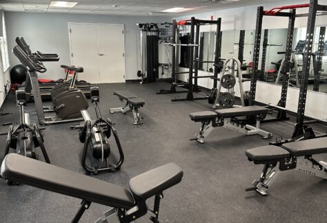 Gym with weight benches, racks, and cardio machines