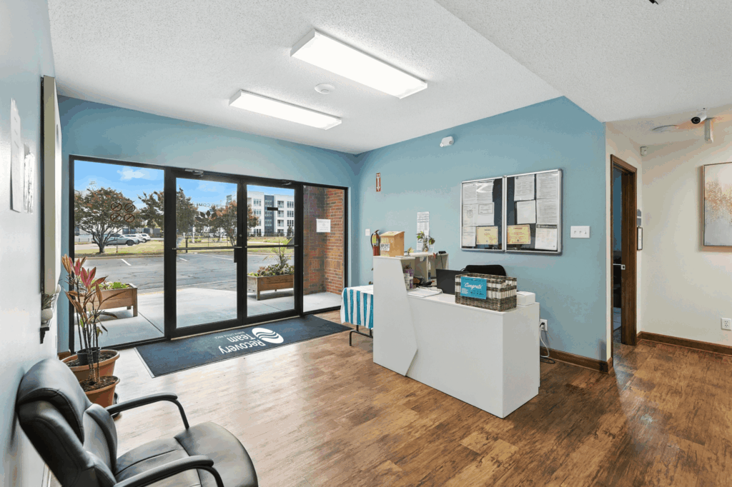 Lobby with glass entry doors, reception desk, and indoor plants.