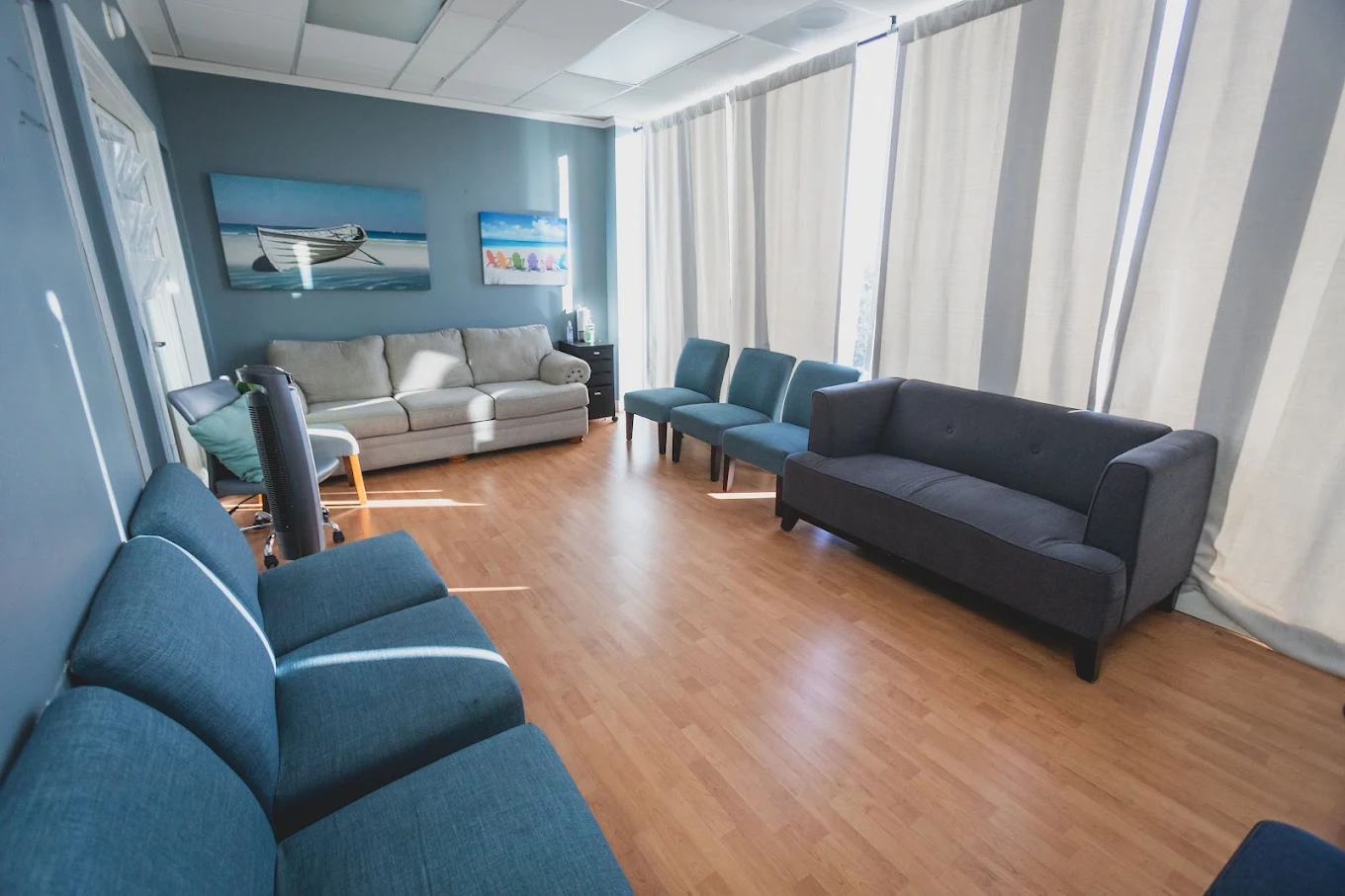 Lounge with blue seating, wood flooring, and large windows