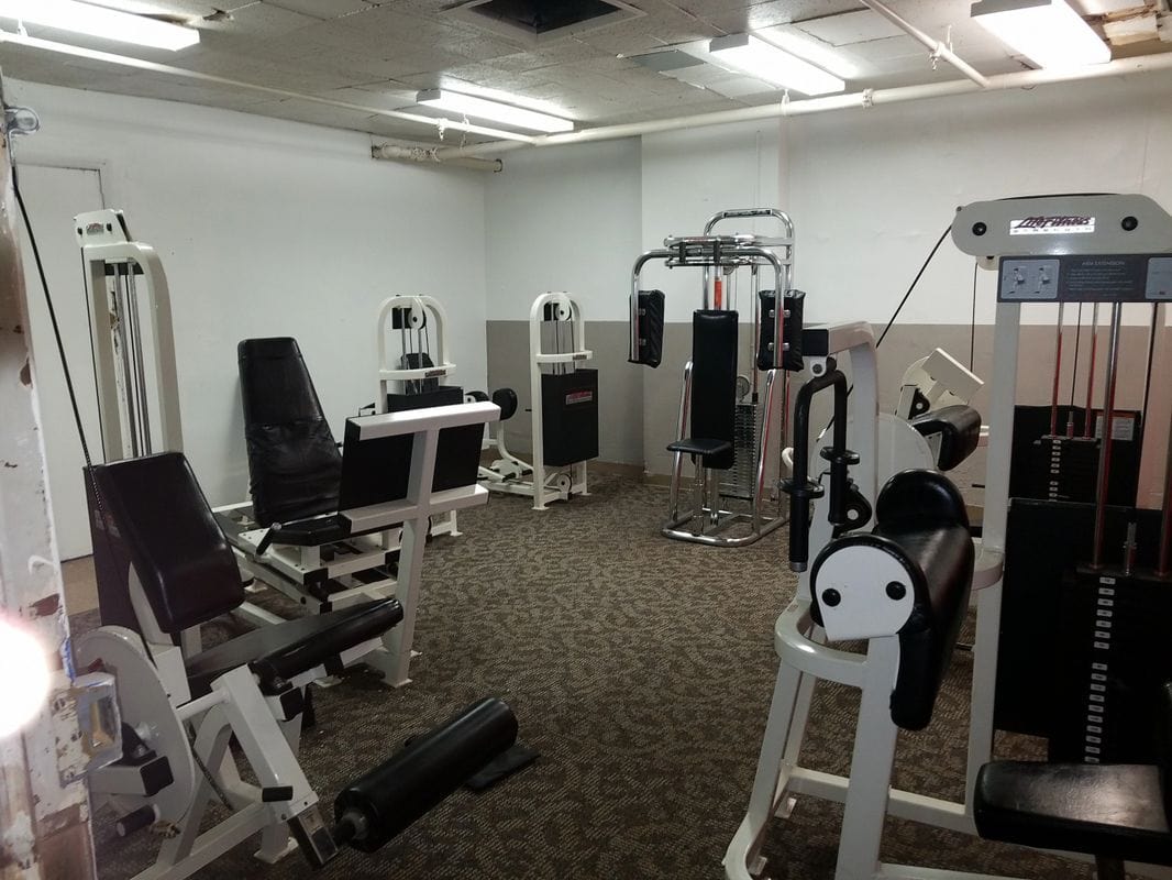 Room with strength training machines and padded workout equipment
