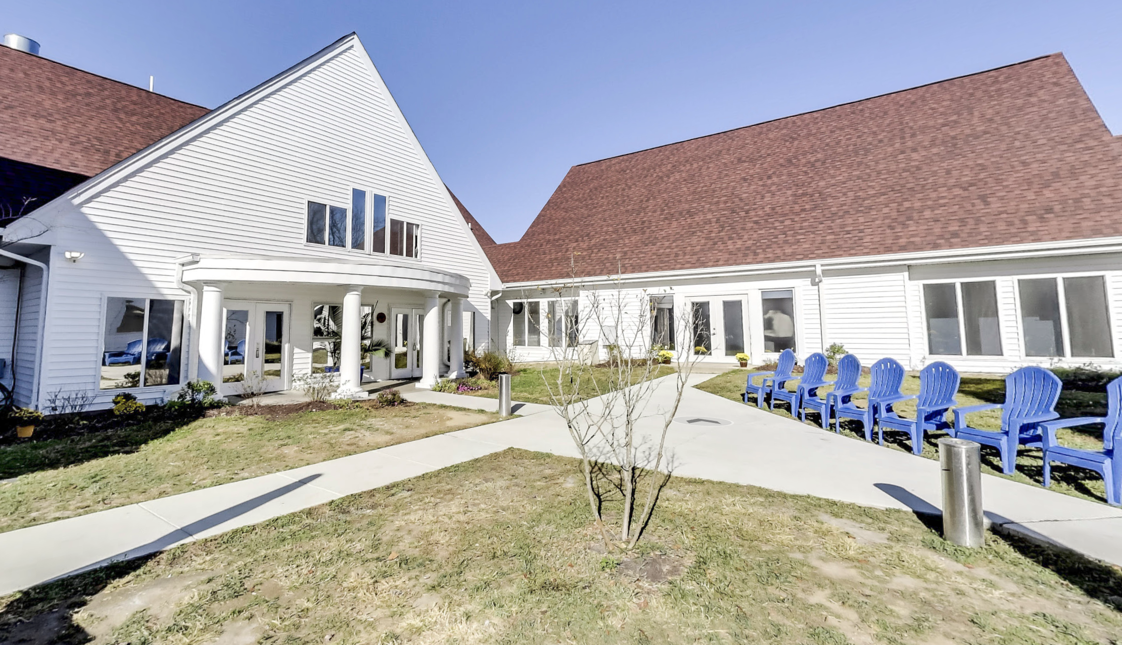 White residential facility with a courtyard and blue chairs