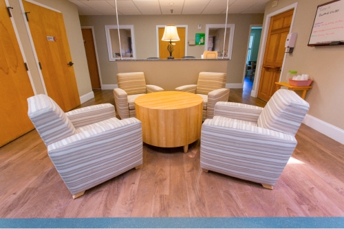 A small seating area with four striped armchairs and a round table.