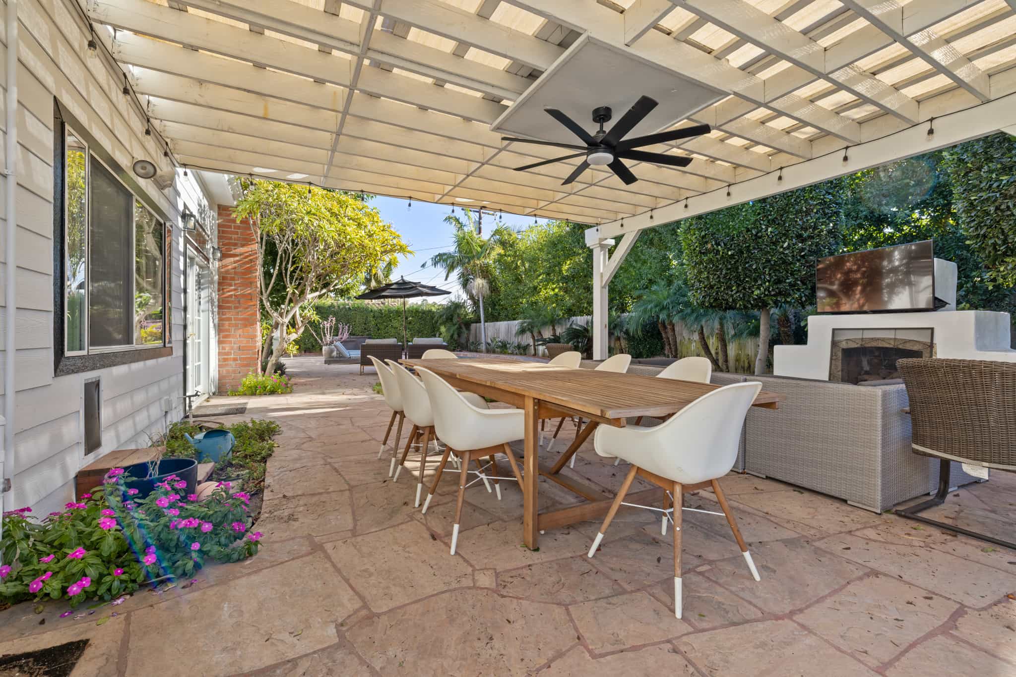 Outdoor patio with dining table, lounge seating, and garden view.