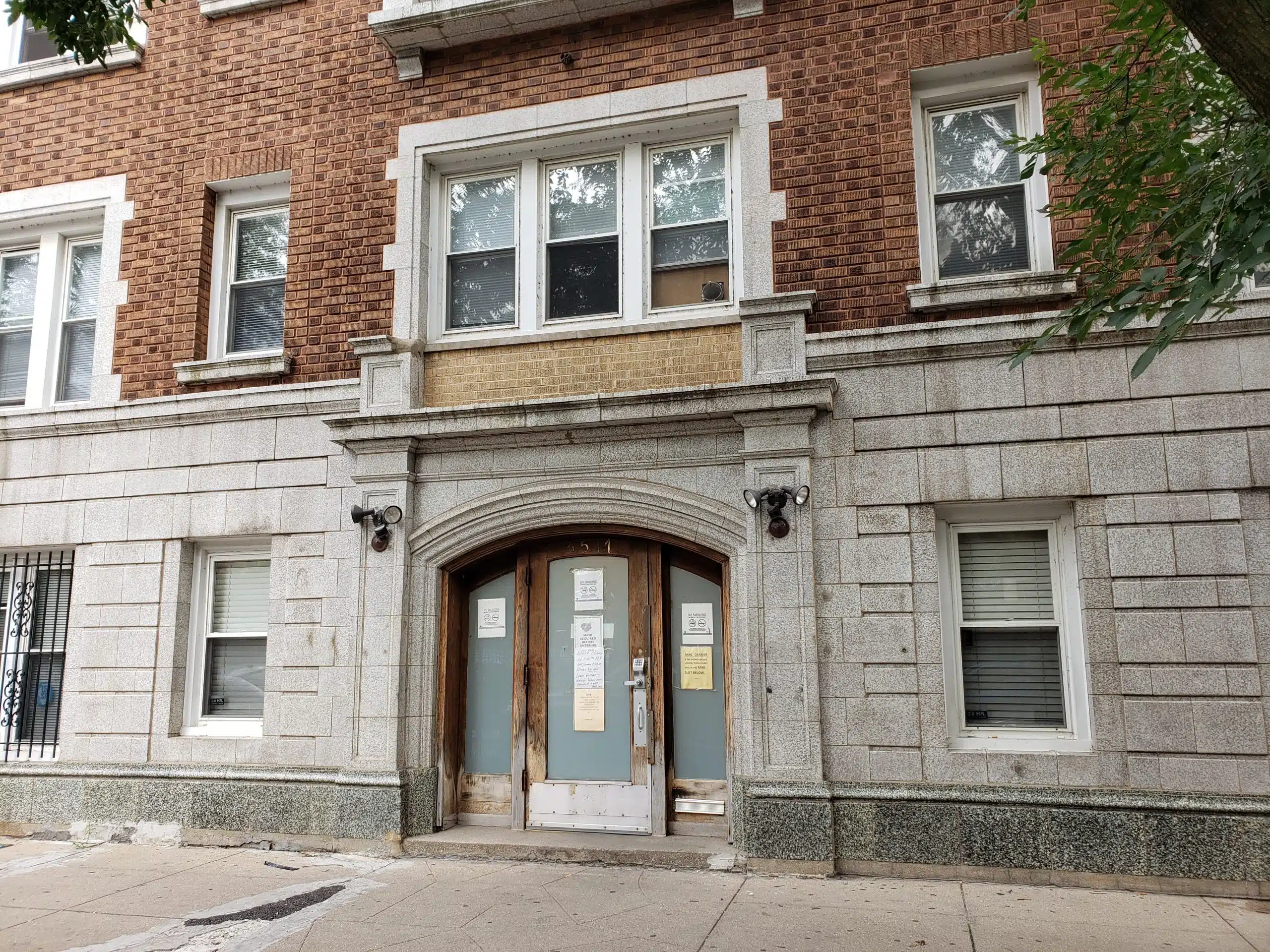 Stone building entrance with double doors and posted notices