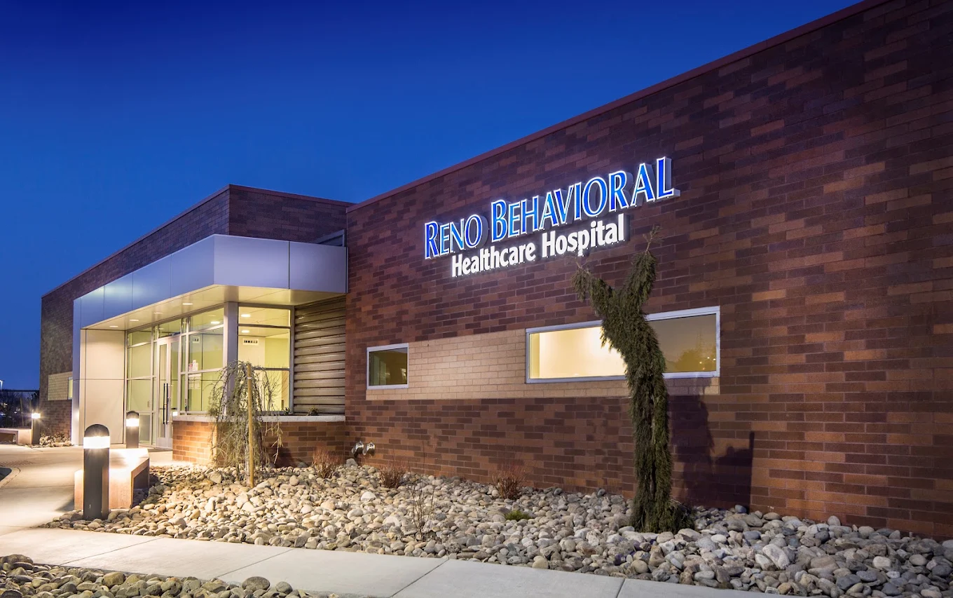 Hospital entrance illuminated at dusk with main signage