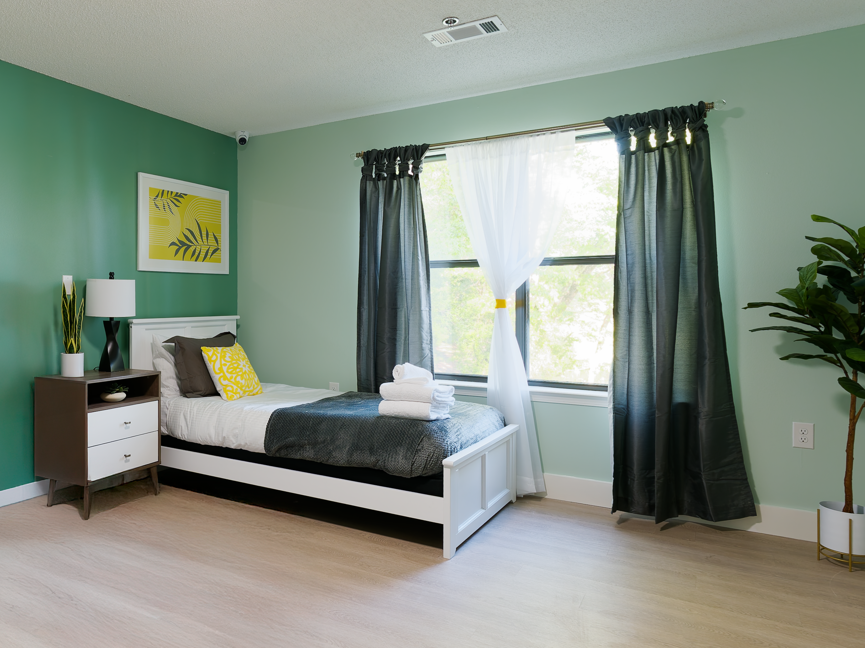 Bright private bedroom with single bed and large window.