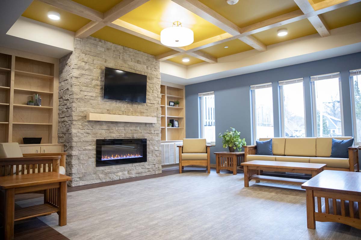 Bright lounge with sofas, stone fireplace, and large windows