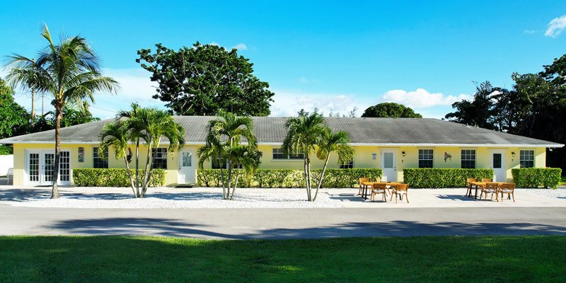 Yellow rehab facility with outdoor seating and palm trees.