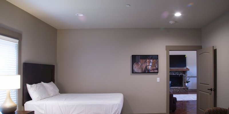 A peaceful bedroom with two neatly made beds, soft lighting from a bedside lamp, and calming decor, including a horse-themed wall art.