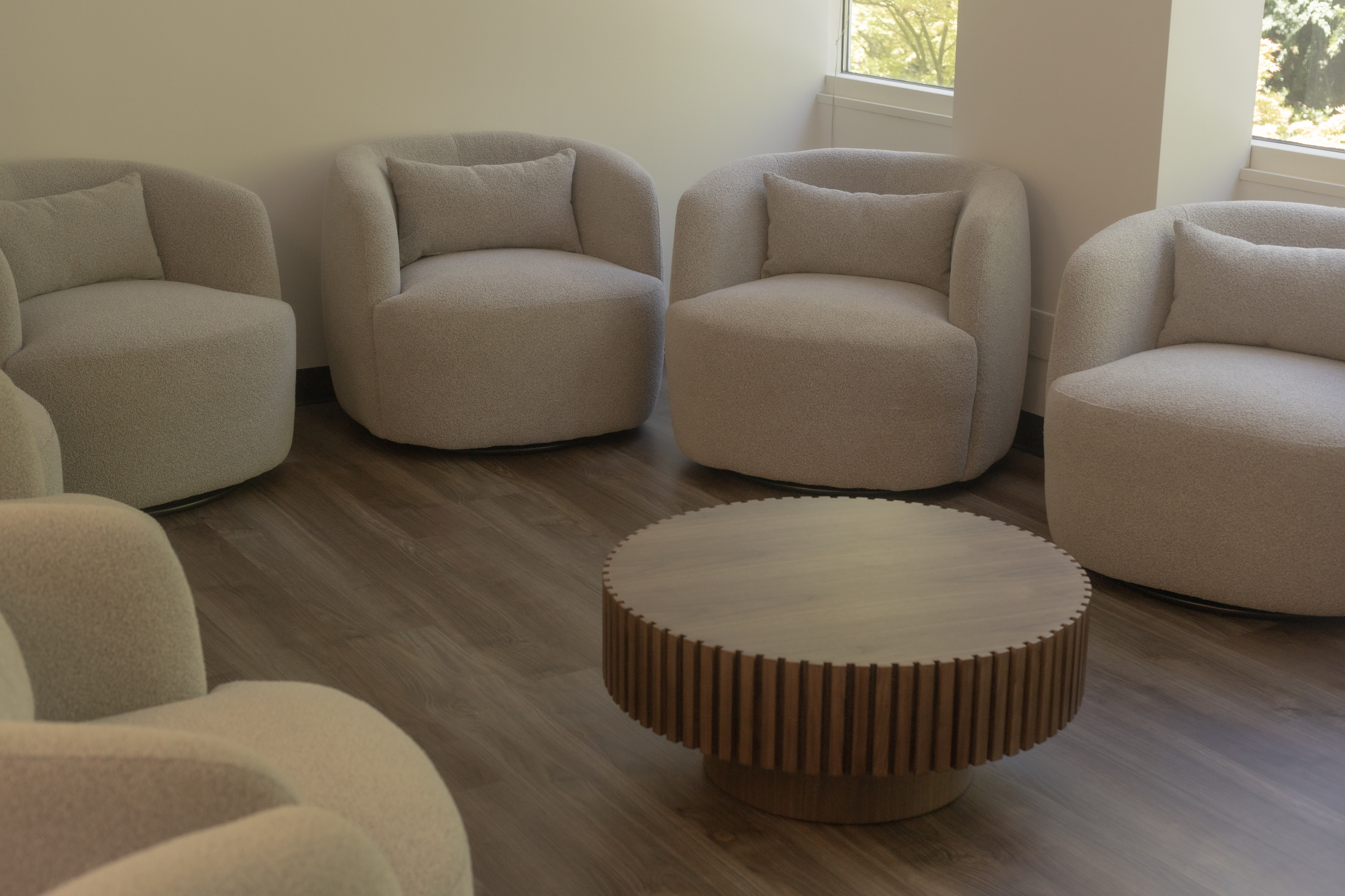  Circle of gray chairs around wood table in therapy room