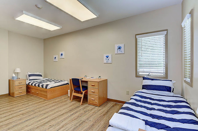 Shared bedroom with two striped twin beds and a wooden desk.