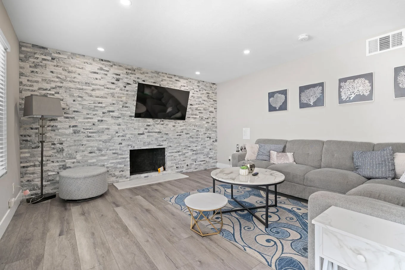 Living room with grey couch, stone fireplace, and TV