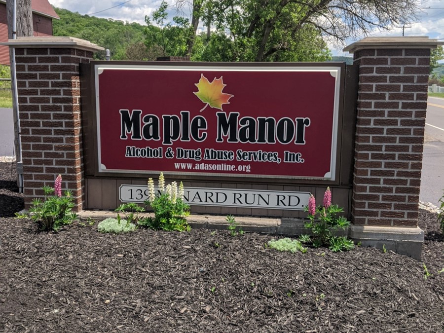 Maple Manor facility sign surrounded by fresh landscaping.