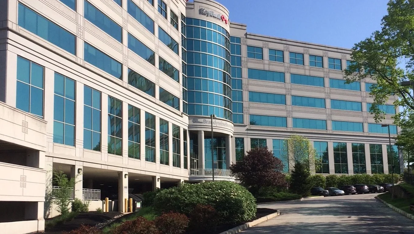 Exterior of a multi-story office building with blue glass windows and landscaped grounds