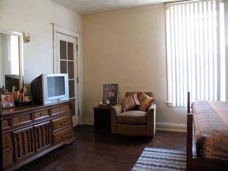 Cozy bedroom with dresser, armchair, and TV