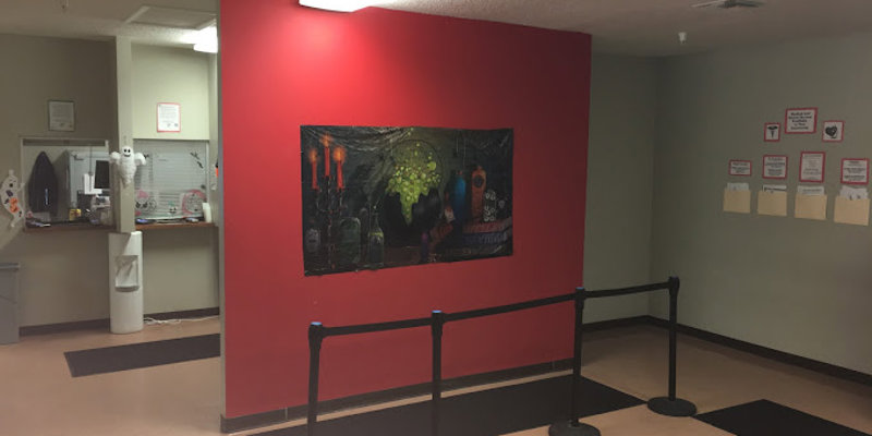 Welcoming reception area with a bold red accent wall, cheerful decor, and clear guidance for check-ins.