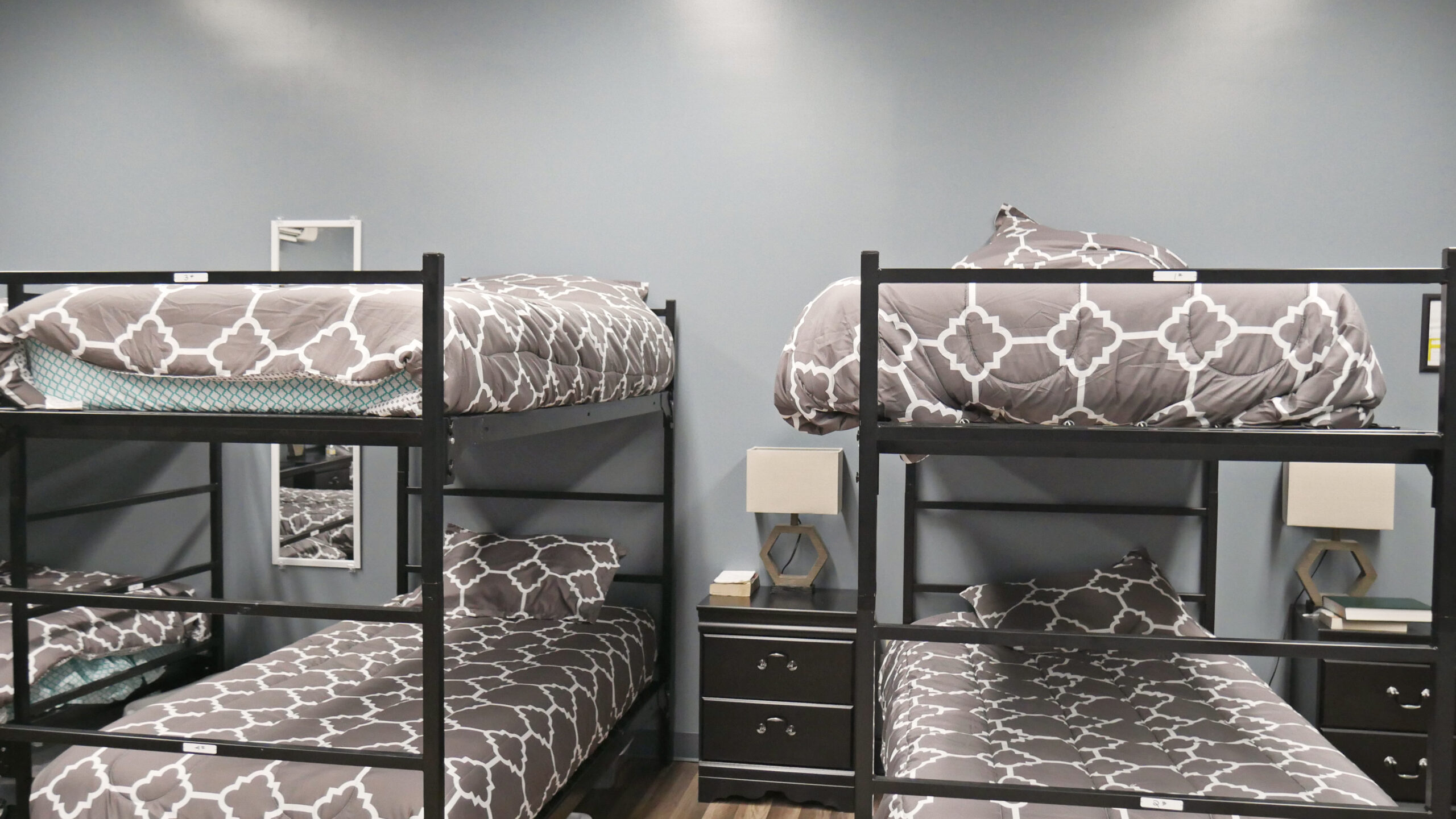 Four bunk beds with gray patterned comforters